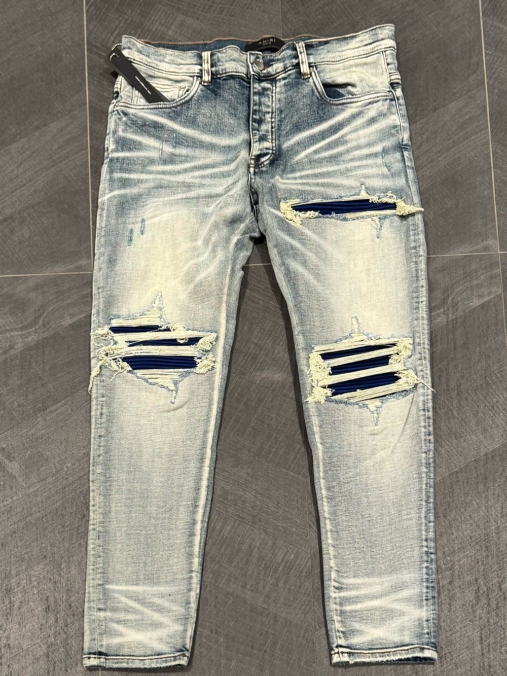AMIRI Light Blue Distressed Skinny Jeans with Navy Patch Accents